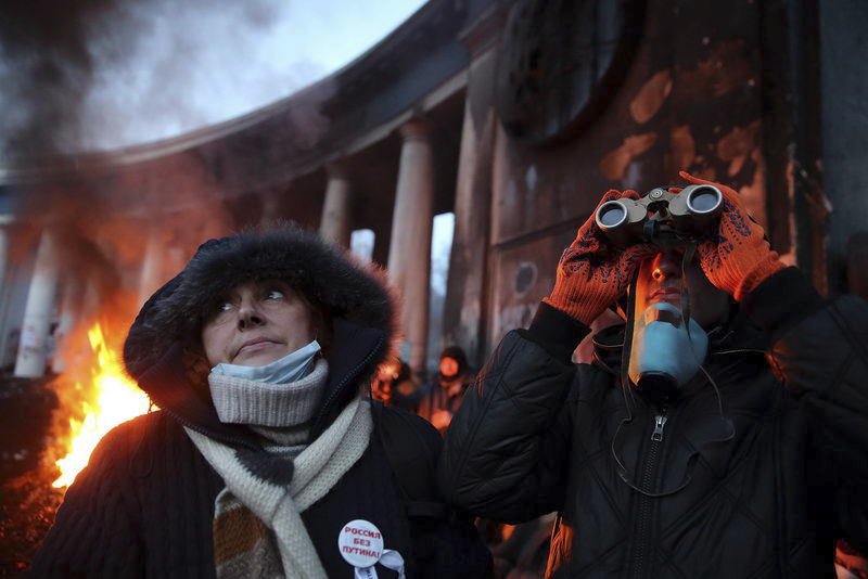 Majdan, Kyjev, Ukrajina 2014. Žena zkoumá dalekohledem pozice pořádkových sil. Její přítelkyně je z Ruska – a nemá ráda Vladimira Putina.