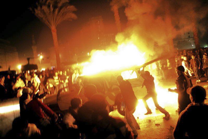 Arabské jaro, Káhira, Egypt, 2011. Rozvášněný dav útočí na policejní vůz. Auto i s posádkou explodovalo.