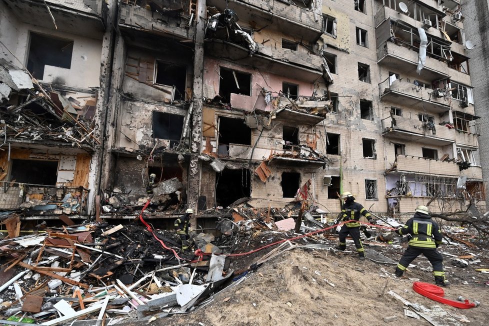 Hasiči pracují v poškozené obytné budově v ulici Koshytsa, předměstí ukrajinského hlavního města Kyjeva, které zasáhla vojenská střela.